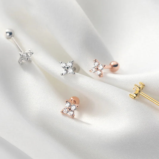 Ästhetische Produktfotografie der blütenförmigen Ohrstecker aus 925er Silber in Silber, Gelbgold und Roségold auf weißem Seidenstoff.