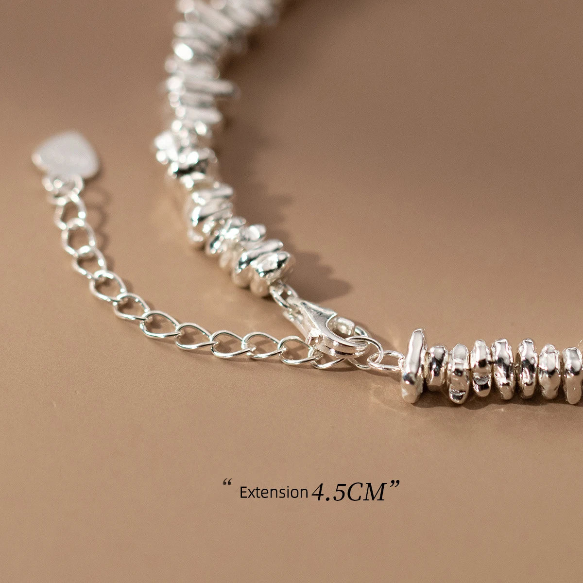 Nahaufnahme des Kettenverschlusses des Armbands aus 925er Silber mit der Maßangabe "verstellbar 4.5CM" und einem kleinen, hängenden Herz-Anhänger.