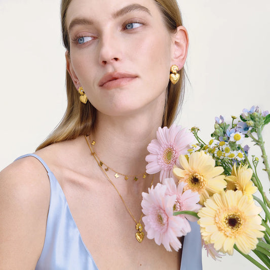 Tragebeispiel der Schmuckkollektion in Kombination mit einem hellblauen Oberteil und Blumen.