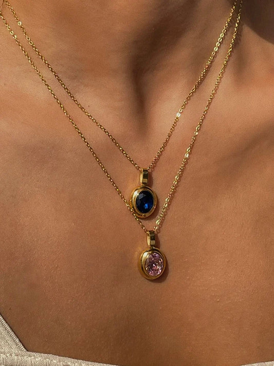 Zwei vergoldete Damen-Halsketten im Layering-Look mit ovalen Rhinestone-Anhängern in Blau und Rosa.