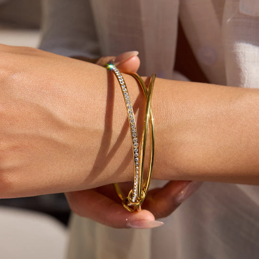 „Eleganter dreireihiger Armreif aus 18K vergoldetem Edelstahl, eine Schiene besetzt mit funkelnden Zirkonia-Steinen im Pavé-Stil.“