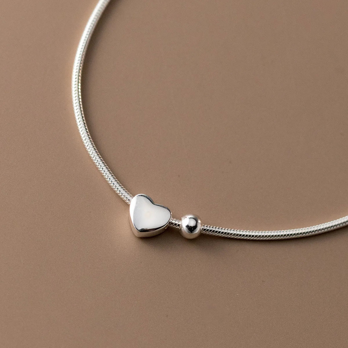 Detail-Nahaufnahme des dreidimensionalen Herz-Elementes und der glatten Schlangenbeads-Kette aus 925 Sterling Silber