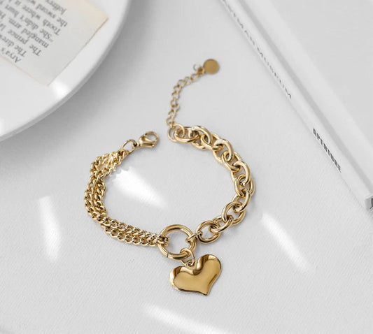 Gliederarmband aus Titan mit 18 Karat Vergoldung, zweigeteiltem Ketten-Design und Herz-Anhänger auf hellem Untergrund