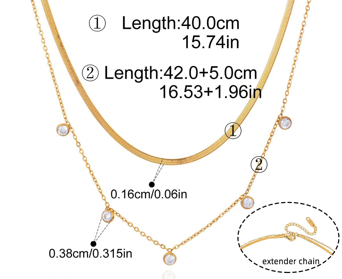 Technisches Produktfoto des geschichteten goldvergoldeten Edelstahl-Kettensets mit Maßen; die feine Kette ist 40 cm lang (15,74 Zoll), die Paperclip-Kette ist 42 cm lang (16,53 Zoll) plus 5 cm (1,96 Zoll) Verlängerung, und die Zirkonia-Steine haben einen Durchmesser von 0,38 cm (0,32 Zoll).