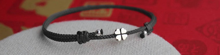 Schwarze Ausführung des handgefertigten Textilarmbands mit vierblättrigem Kleeblatt-Anhänger aus 925er Sterling Silber.