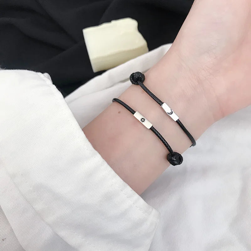 Zwei Handgelenke tragen zusammen die zusammenpassenden schwarzen Partner-Armbänder mit Sonne und Mond.