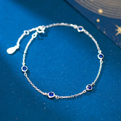 Draufsicht des verstellbaren Silberarmbands mit blauen Zirkonia-Steinen auf blauem Hintergrund.