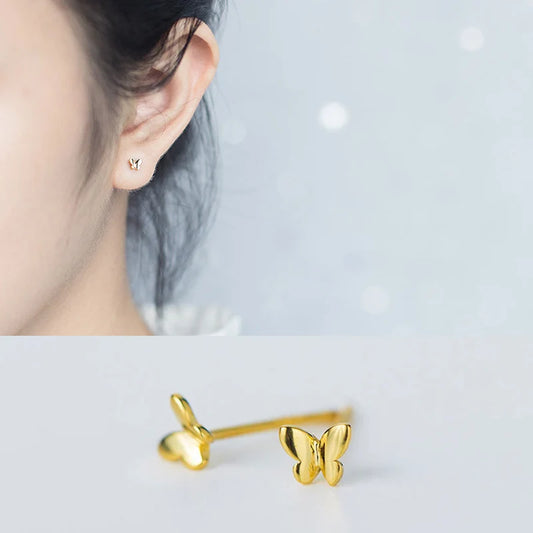 Minimalistischer Helix- und Ohrläppchen-Schmuck: Schmetterlings-Ohrstecker aus Gold am Ohr getragen.