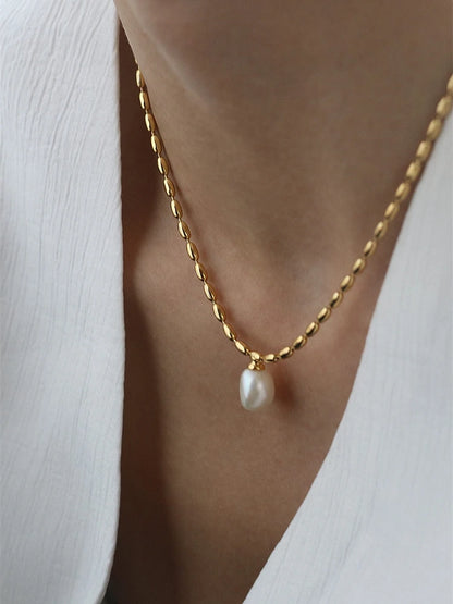 Nahaufnahme einer eleganten Titan-Halskette mit 18K Vergoldung im Reiskorn-Design und einem Anhänger aus einer echten, tropfenförmigen Süßwasserperle.