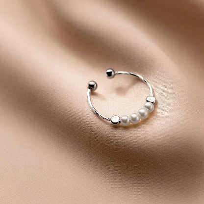 „Seitenansicht des zierlichen Silber-Perlenrings, die die Struktur der Ringschiene und die Fassung der Perlen zeigt.“