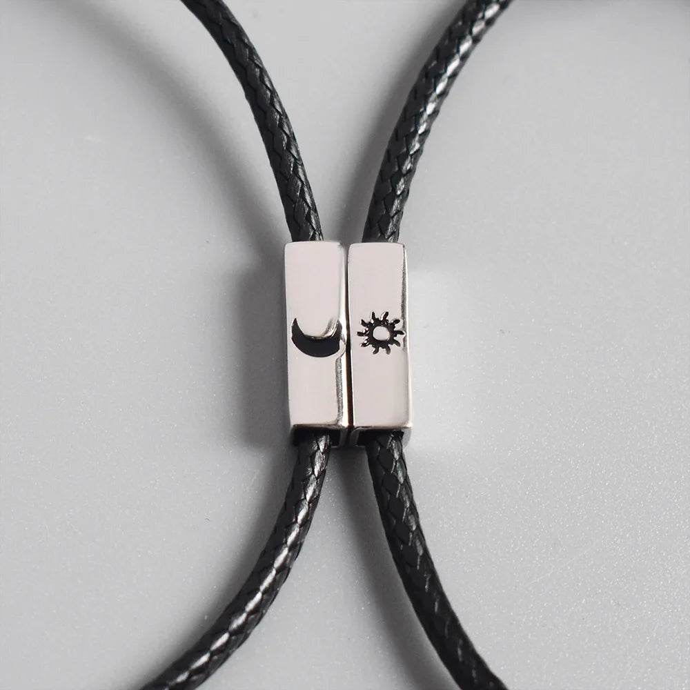Nahaufnahme der beiden zusammengefügten Kordelarmbänder mit eingravierten Symbolen für Sonne und Mond.