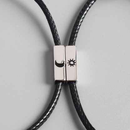 Nahaufnahme der beiden zusammengefügten Kordelarmbänder mit eingravierten Symbolen für Sonne und Mond.