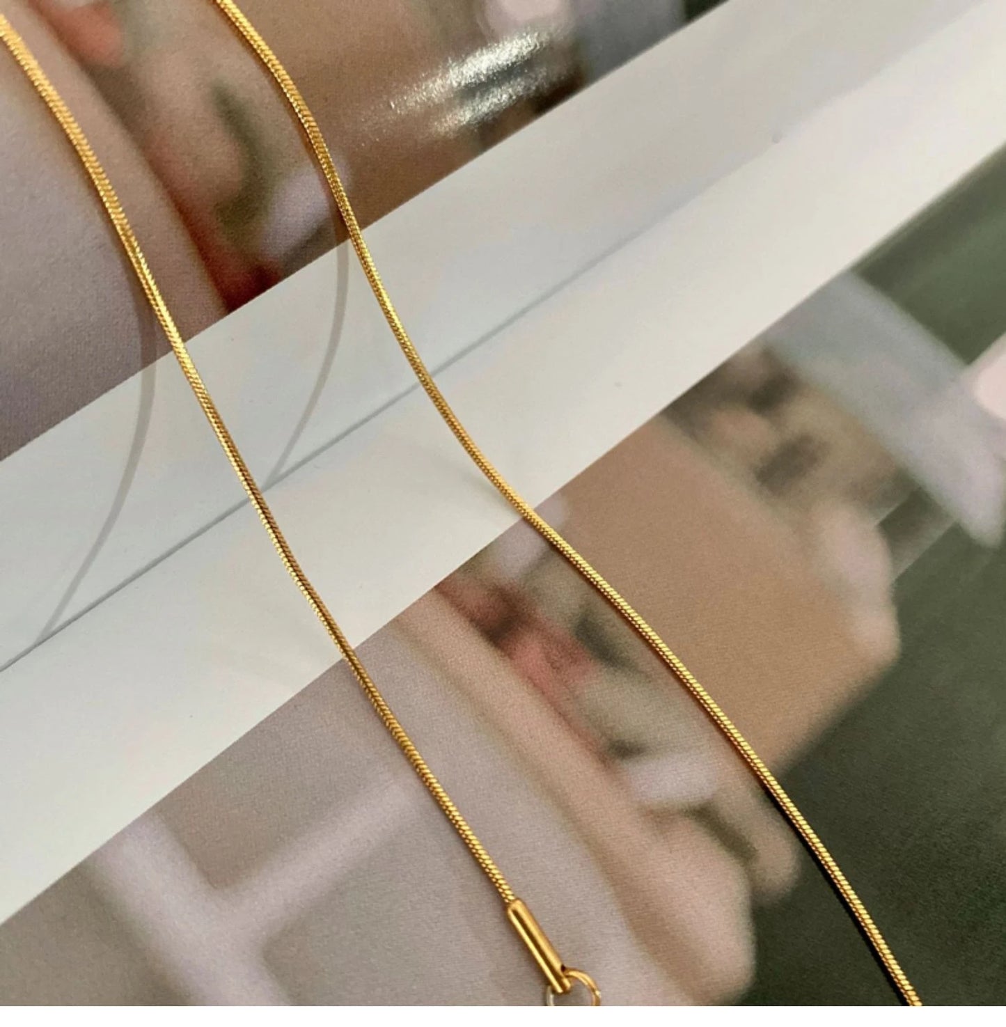 Detailaufnahme einer flachen, vergoldeten Schlangenkette aus Titan | goldene Kette im Herringbone-Stil