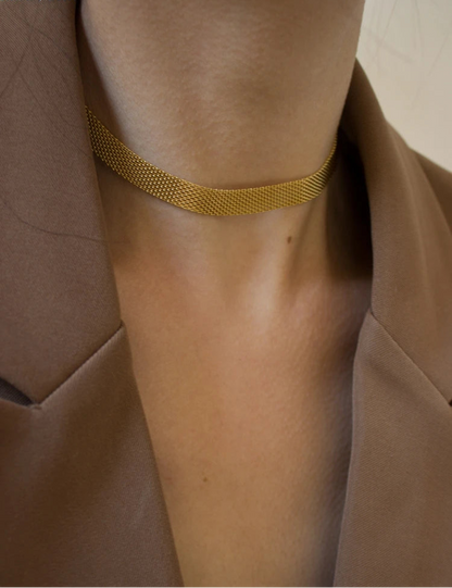 Goldene, flache Schlangenkette an Frau getragen | Schimmernder, kurzer Halsschmuck zum Blazer | Gold-Kette elegant