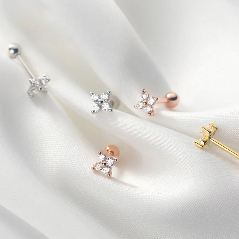 Ästhetische Produktfotografie der blütenförmigen Ohrstecker aus 925er Silber in Silber, Gelbgold und Roségold auf weißem Seidenstoff.