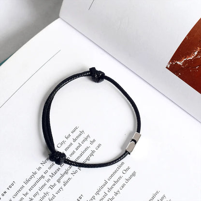 Draufsicht auf das schwarze Partner-Armband mit Mond-Motiv präsentiert auf Buchseiten.