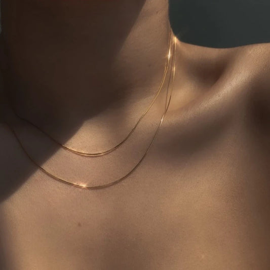 Flache Schlangenkette in Gold getragen | schimmerndes Collier aus 18K vergoldetem Titan | dezenter Halsschmuck