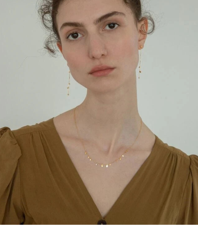 Model trägt eine dezente Halskette aus 18K vergoldetem Titan | kurze Goldkette mit kleinen Anhängern | eleganter Halsschmuck