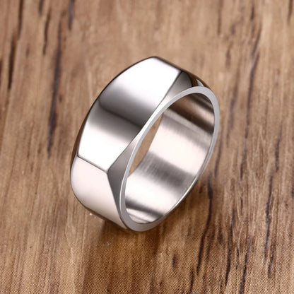 Nahaufnahme eines geometrischen Herrenrings aus hochglanzpoliertem Edelstahl mit abgeflachter Oberseite, präsentiert auf einer Holzoberfläche.