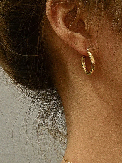 Detailliertes Seitenprofil einer Frau, die schlichte, glänzende 18K vergoldete Creolen trägt.