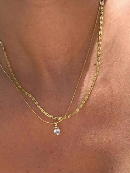 Weitere Ansicht einer Frau, die die goldene Kette mit dem rechteckigen Zirkonia-Anhänger zusammen mit einer feineren Kette im Schicht-Look (Layering) trägt.