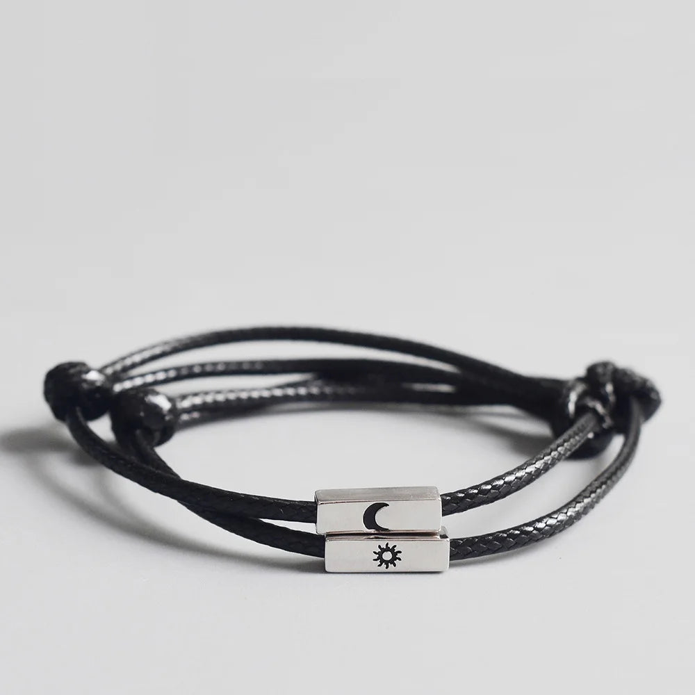 Nahaufnahme des schwarzen Partner-Armband-Sets aus Kordel mit rechteckigen silbernen Metall-Elementen und gravierter Sonne und Mond.