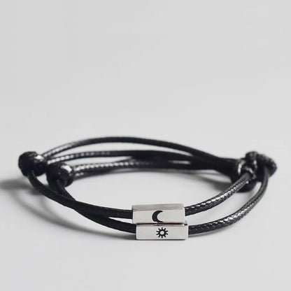 Nahaufnahme des schwarzen Partner-Armband-Sets aus Kordel mit rechteckigen silbernen Metall-Elementen und gravierter Sonne und Mond.