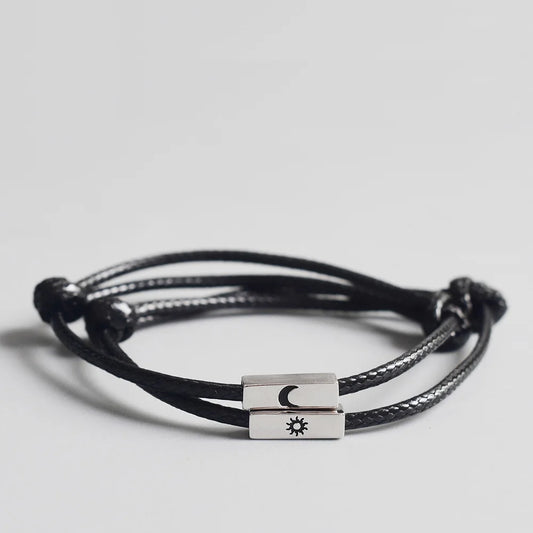Nahaufnahme des schwarzen Partner-Armband-Sets aus Kordel mit rechteckigen silbernen Metall-Elementen und gravierter Sonne und Mond.