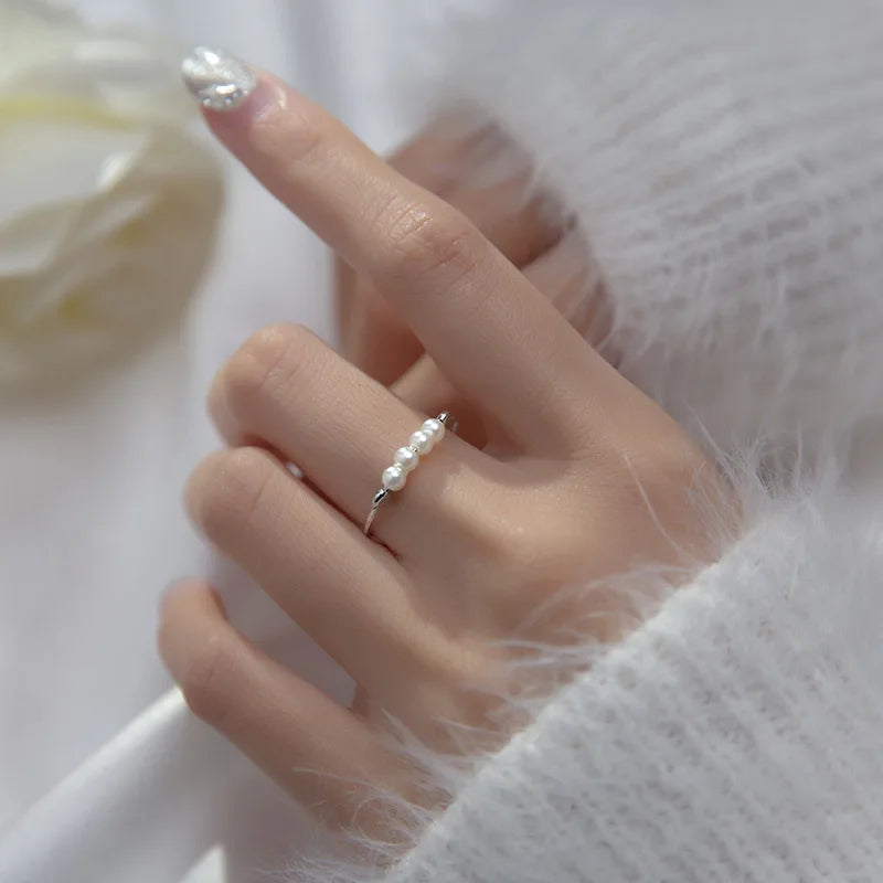 „Detaillierte Nahaufnahme eines zierlichen Perlen-Damenrings aus 925er Silber an einem gepflegten Finger.“