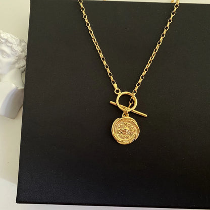 Produktansicht der 18K vergoldeten Messing-Kette mit Münzanhänger elegant präsentiert auf schwarzem Untergrund.