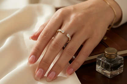 „Modische Modellansicht eines verstellbaren Goldrings mit Zirkonia-Besatz am Zeigefinger, kombiniert mit mehreren goldenen Armbändern im Hintergrund.“