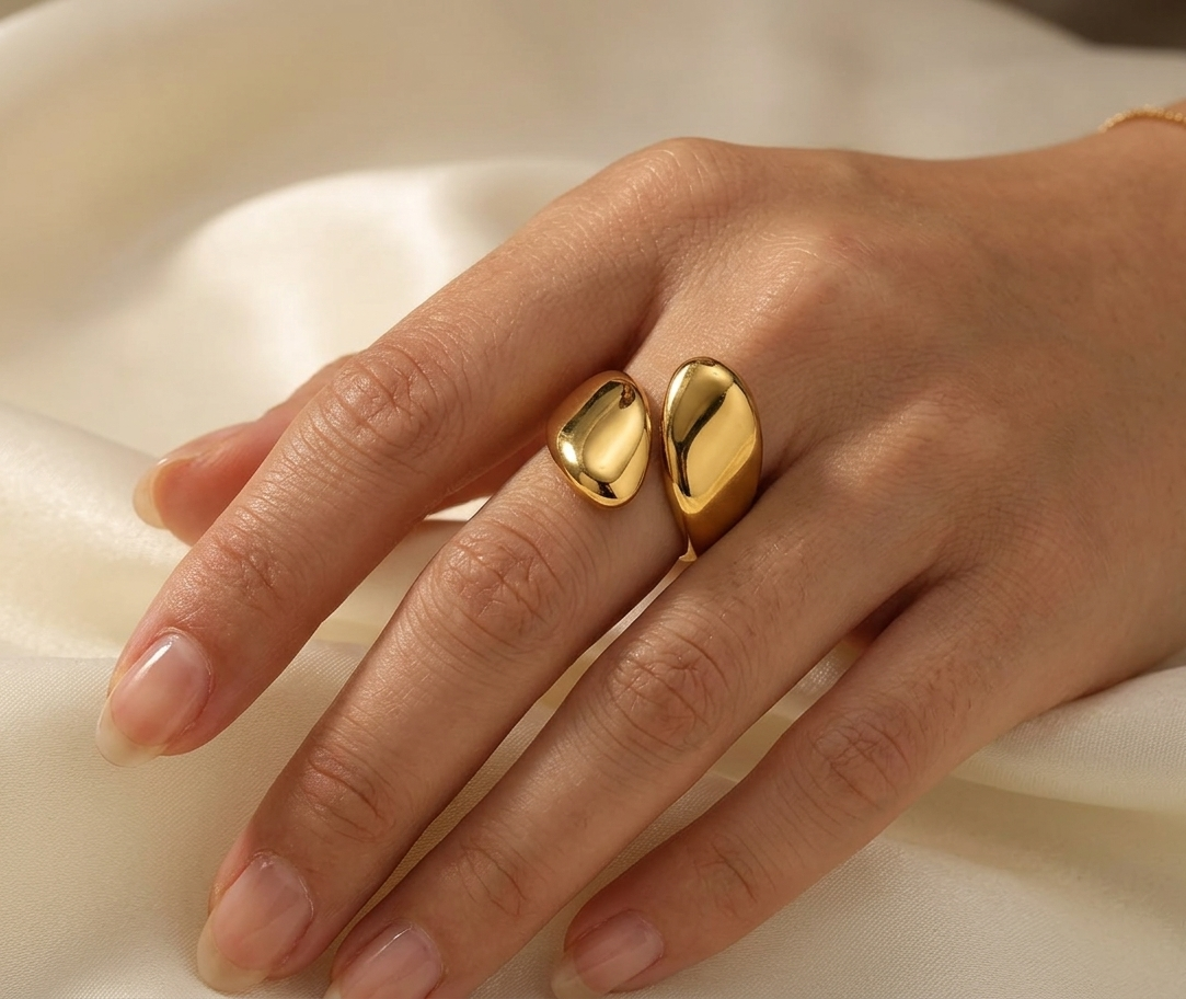 Detaillierte Nahaufnahme der Hand einer Frau, die den asymmetrischen, gold vergoldeten Edelstahlring am Zeigefinger trägt, um die Passform und das offene Bypass-Design zu zeigen.