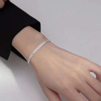 Elegantes Tragebild am Handgelenk: Silbernes Mesh-Gliederarmband zu einem schwarzen Blazer kombiniert