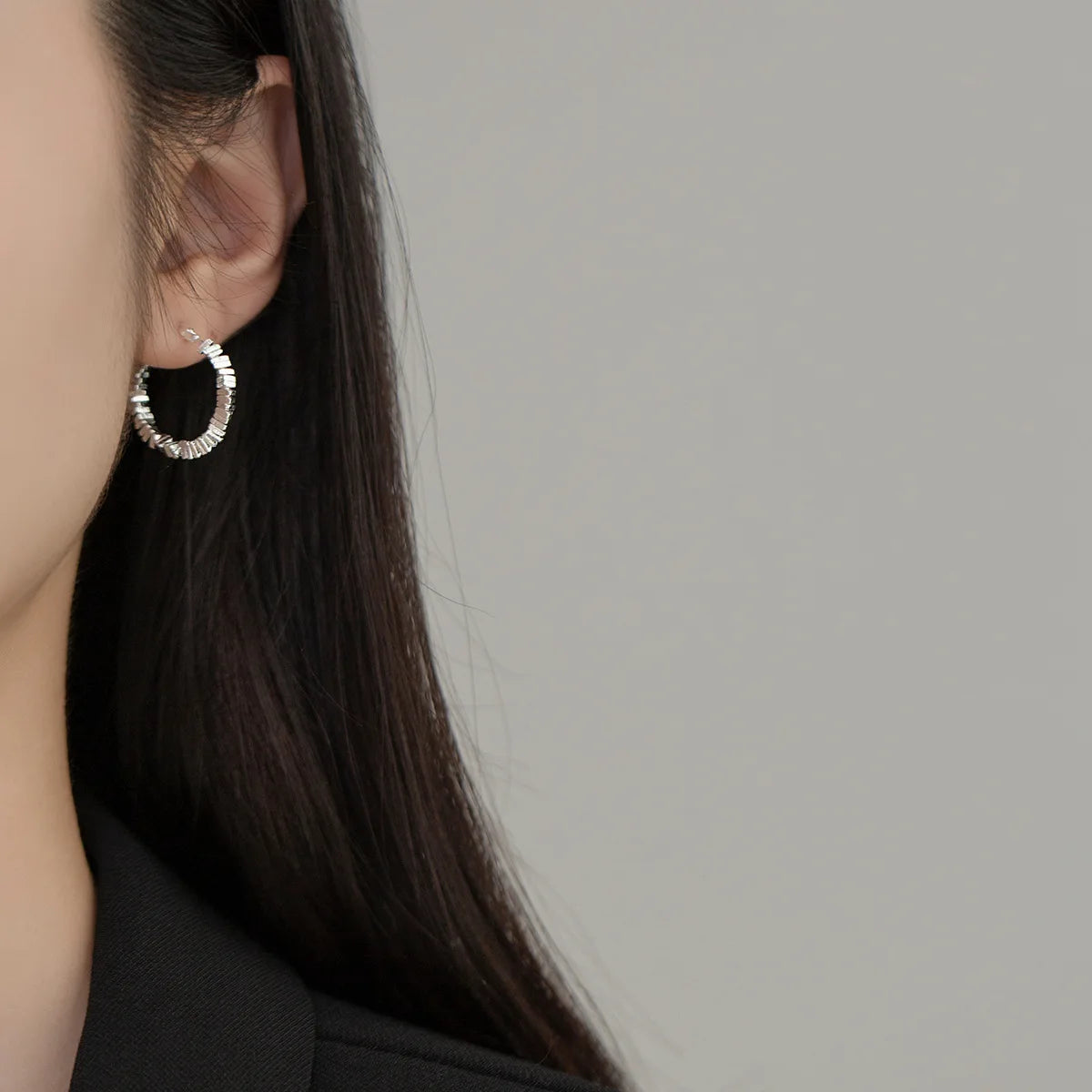  Nahaufnahme des Ohrs einer Frau, die eine kleine, strukturierte Kreole (925er Silber) trägt.

