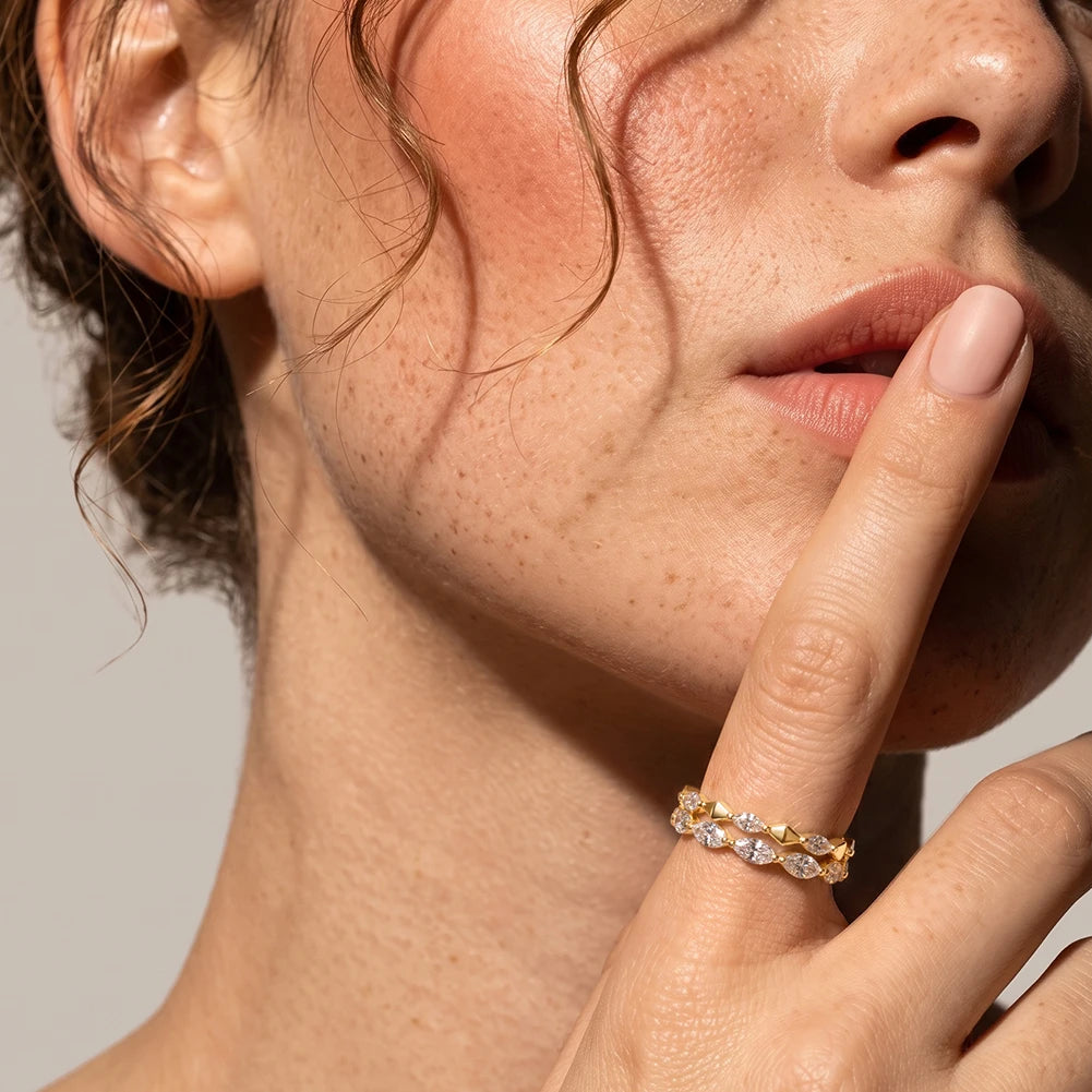 Elegantes Portrait-Tragebild: Vergoldeter Marquise-Zirkonia Bandring stilvoll am Zeigefinger vor dem Gesicht präsentiert.