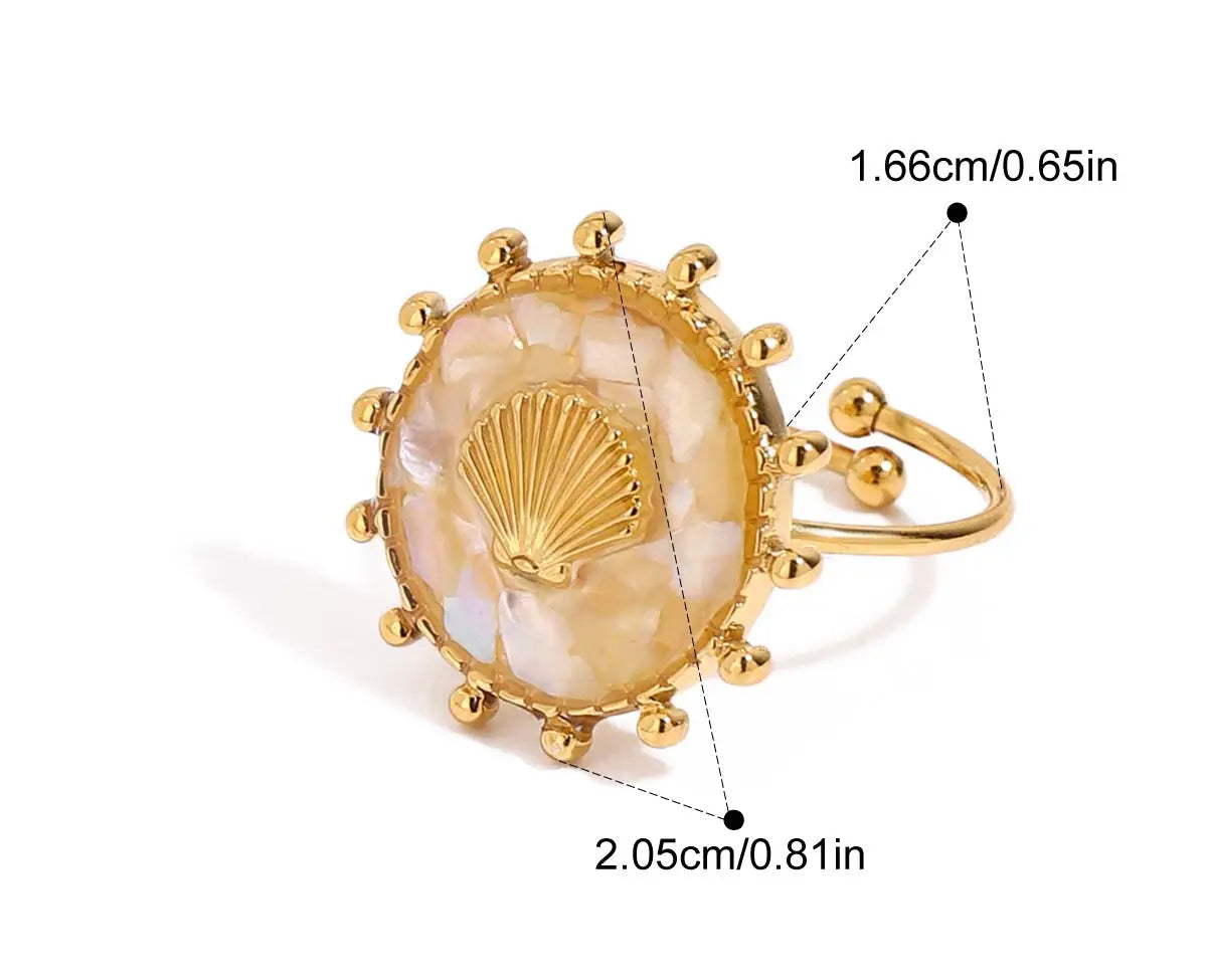 Nahaufnahme eines Rings aus 18K vergoldetem Edelstahl mit einem Muschel-Symbol, umgeben von goldenen Strahlen. Der Ring hat eine Innendurchmesser von 1,66 cm und eine Breite von 2,05 cm.

