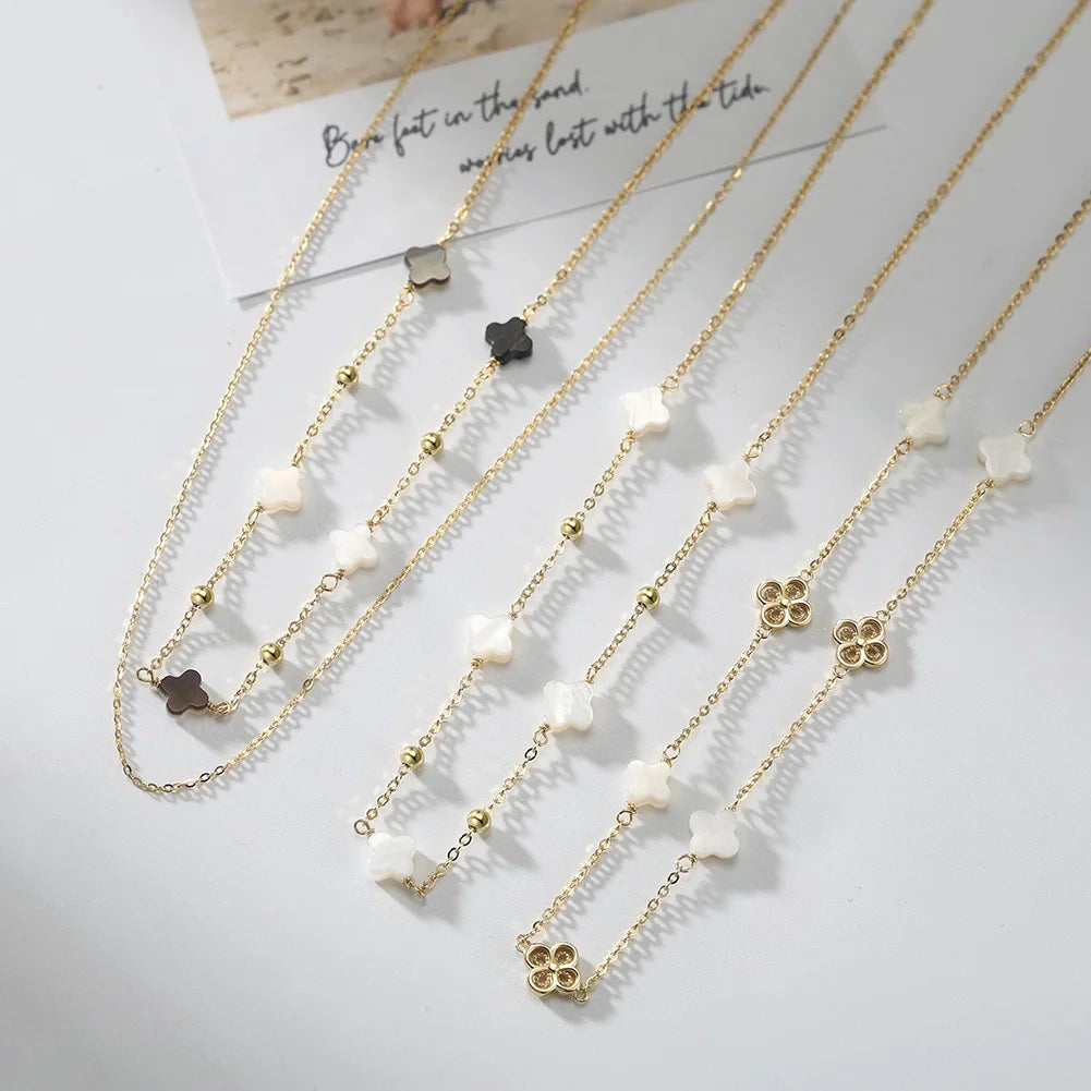 Mehrere goldene Halsketten mit beigen vierblättrigen Kleeblättern und Kügelchen.