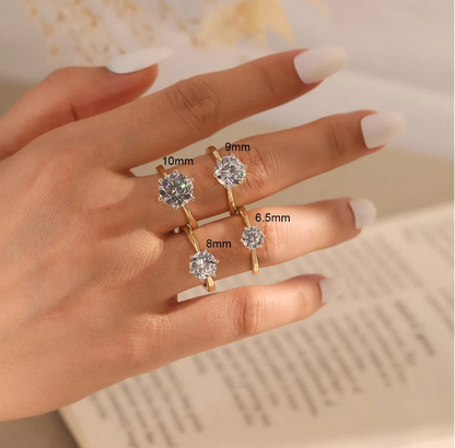 Eine Hand trägt mehrere goldfarbene, verstellbare Ringe aus vergoldetem 925er Silber, alle mit einem einzelnen Zirkonia-Stein besetzt, in vier verschiedenen Größen.