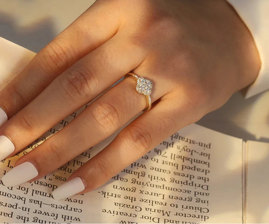 Nahaufnahme einer Hand, die einen Ring mit Kleeblatt-Motiv aus 925er Silber und Zirkonia an einem Finger trägt, während sie ein Buch liest.