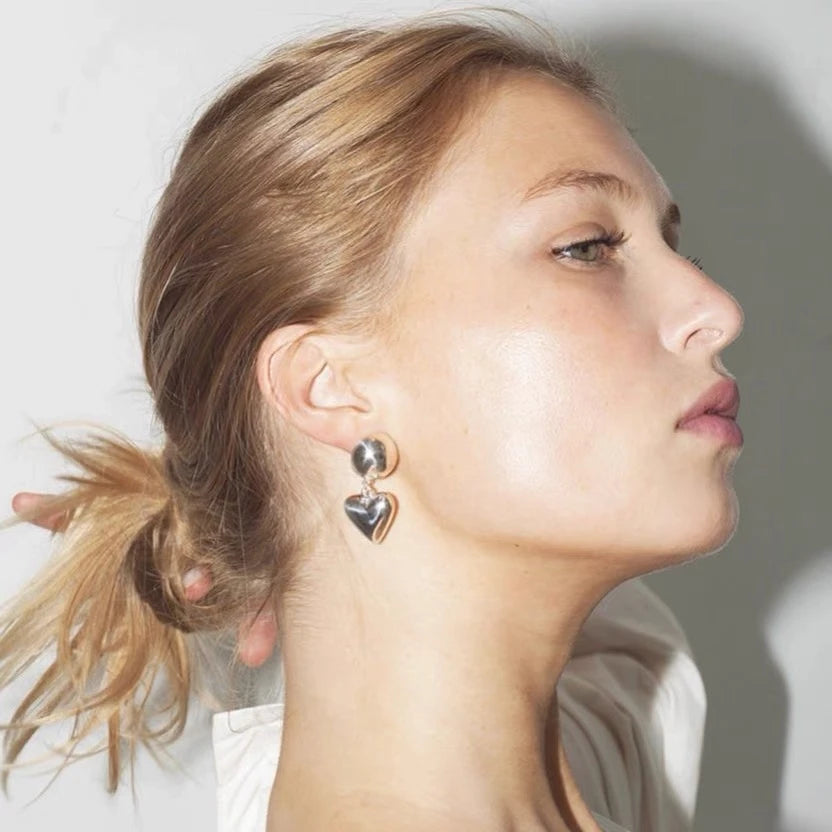 Porträtansicht eines Models, das die silbernen Kugel-Herz-Ohrringe im Profil zeigt, minimalistischer Look