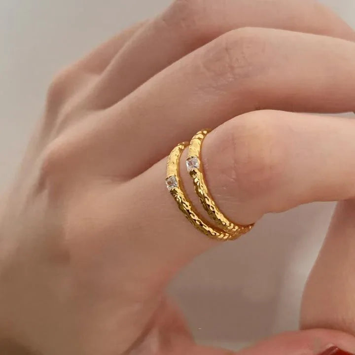 Nahaufnahme der Hand: Schmaler, 18K vergoldeter Messingring mit gehammerter Textur und funkelndem Zirkonia-Stein.