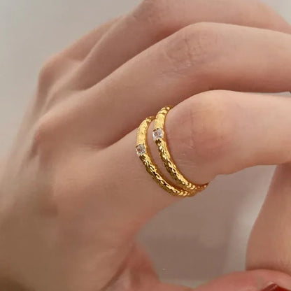 Nahaufnahme der Hand: Schmaler, 18K vergoldeter Messingring mit gehammerter Textur und funkelndem Zirkonia-Stein.