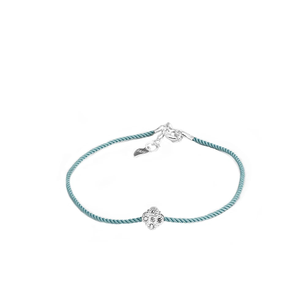  Armband mit mintgrünem Textilband, das einen kleinen runden Anhänger aus 925er Silber mit einem zentralen Zirkoniastein und einen Verschluss mit einem kleinen Herz-Detail zeigt.