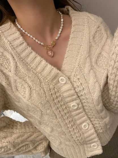 Naturperlenkette mit vergoldetem Titan-Knebelverschluss und altrosafarbenem Herz-Anhänger zu einem beigen Cardigan.