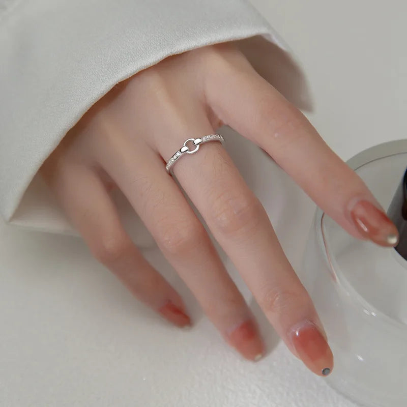 Filigraner Ring aus 925er Sterling Silber mit einem eleganten Knoten-Design und funkelndem Zirkonia-Besatz, getragen an der Hand einer Frau.