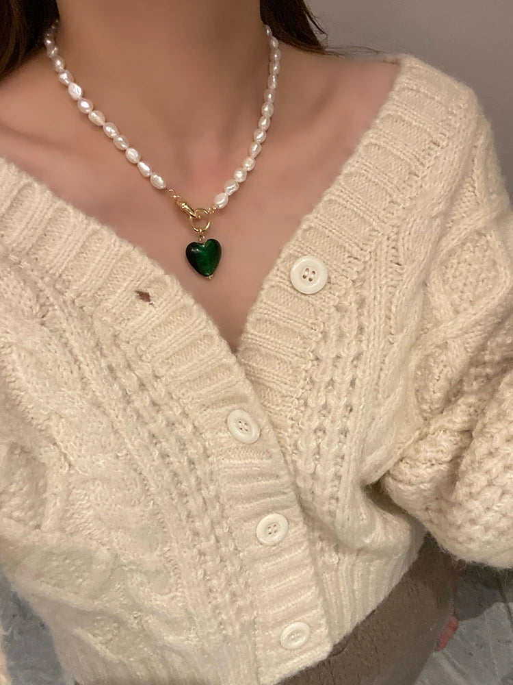 Tragestyling einer Naturperlenkette mit vergoldeter Knebel-Schließe und dunkelgrünem Herz-Anhänger.