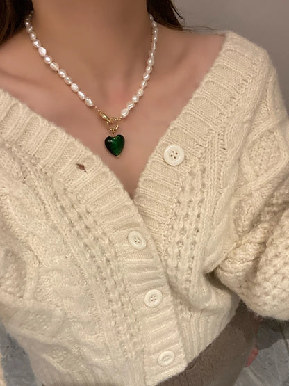 Tragestyling einer Naturperlenkette mit vergoldeter Knebel-Schließe und dunkelgrünem Herz-Anhänger.