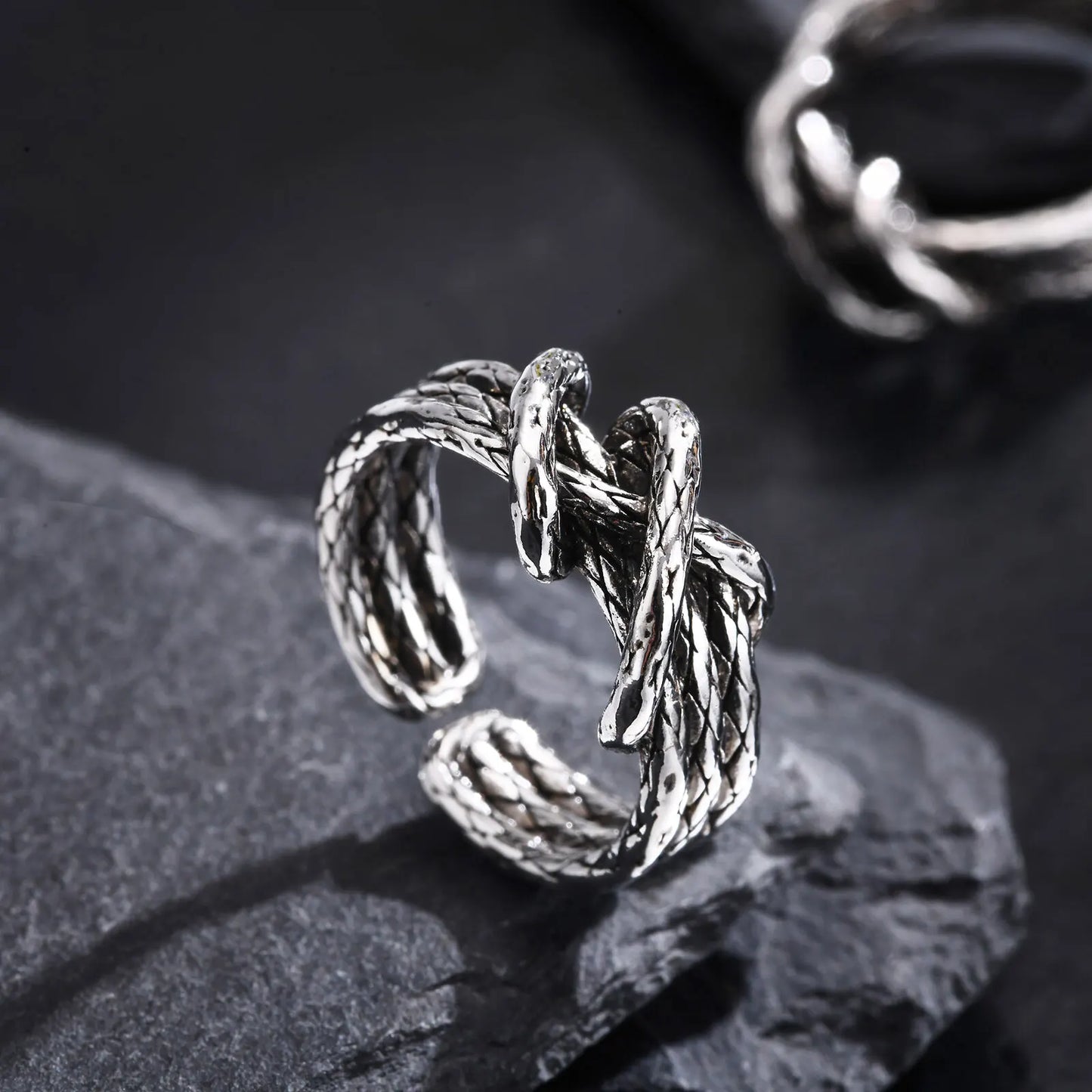 Detailansicht des offenen Edelstahl-Knotenrings liegend auf einer dunklen Oberfläche.