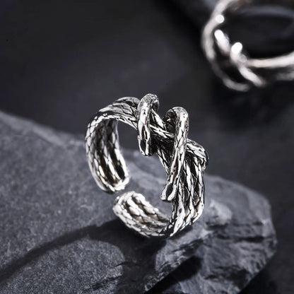 Detailansicht des offenen Edelstahl-Knotenrings liegend auf einer dunklen Oberfläche.