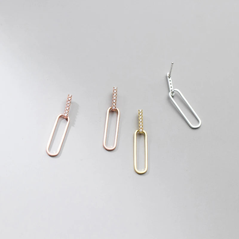 Farbvarianten-Übersicht der geometrischen 925er Silber-Ohrstecker in Roségold, Gelbgold und Silber auf grauem Untergrund.